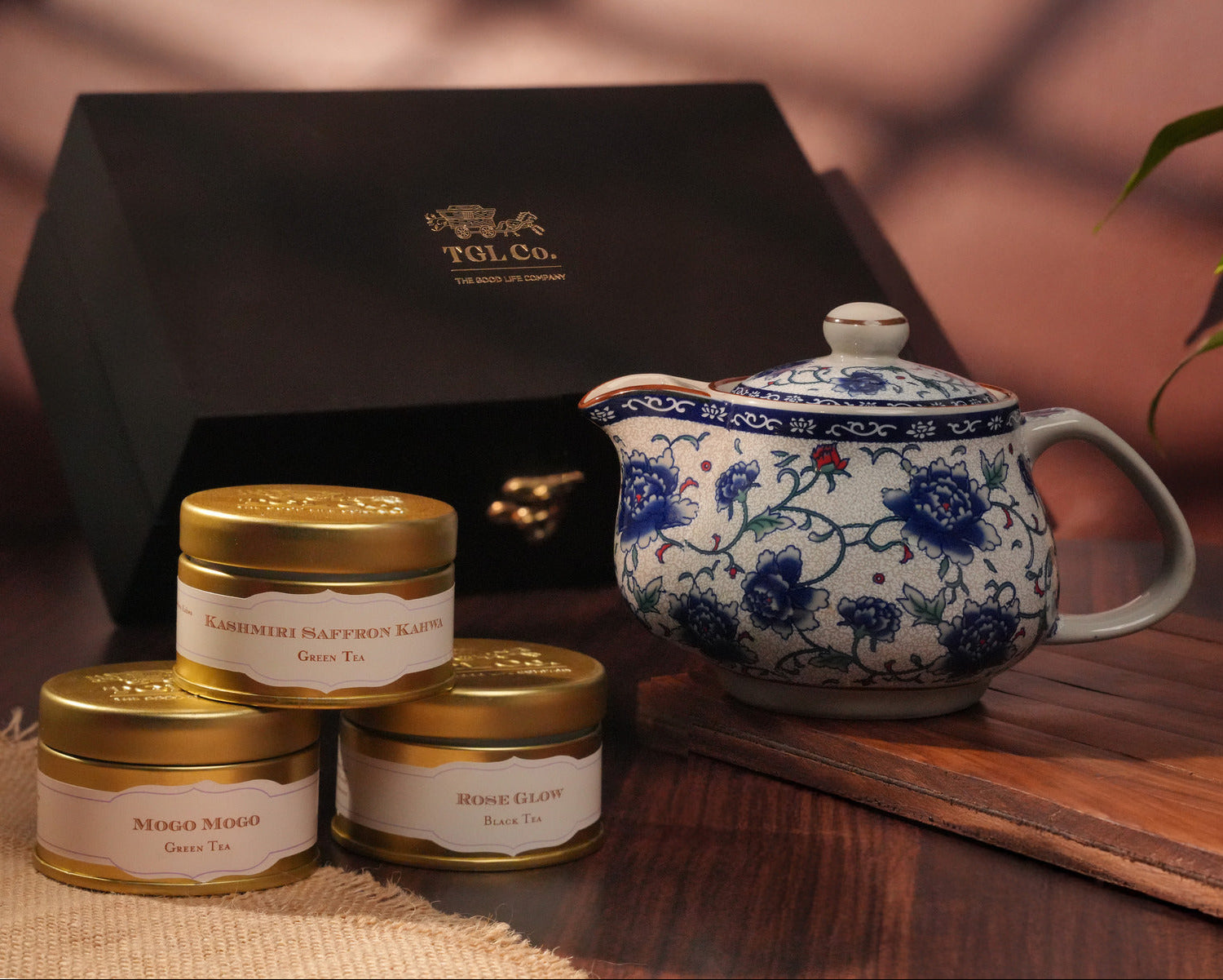 Tea set with teapot and tea tins on a wooden surface, featuring TGL Co. branding.