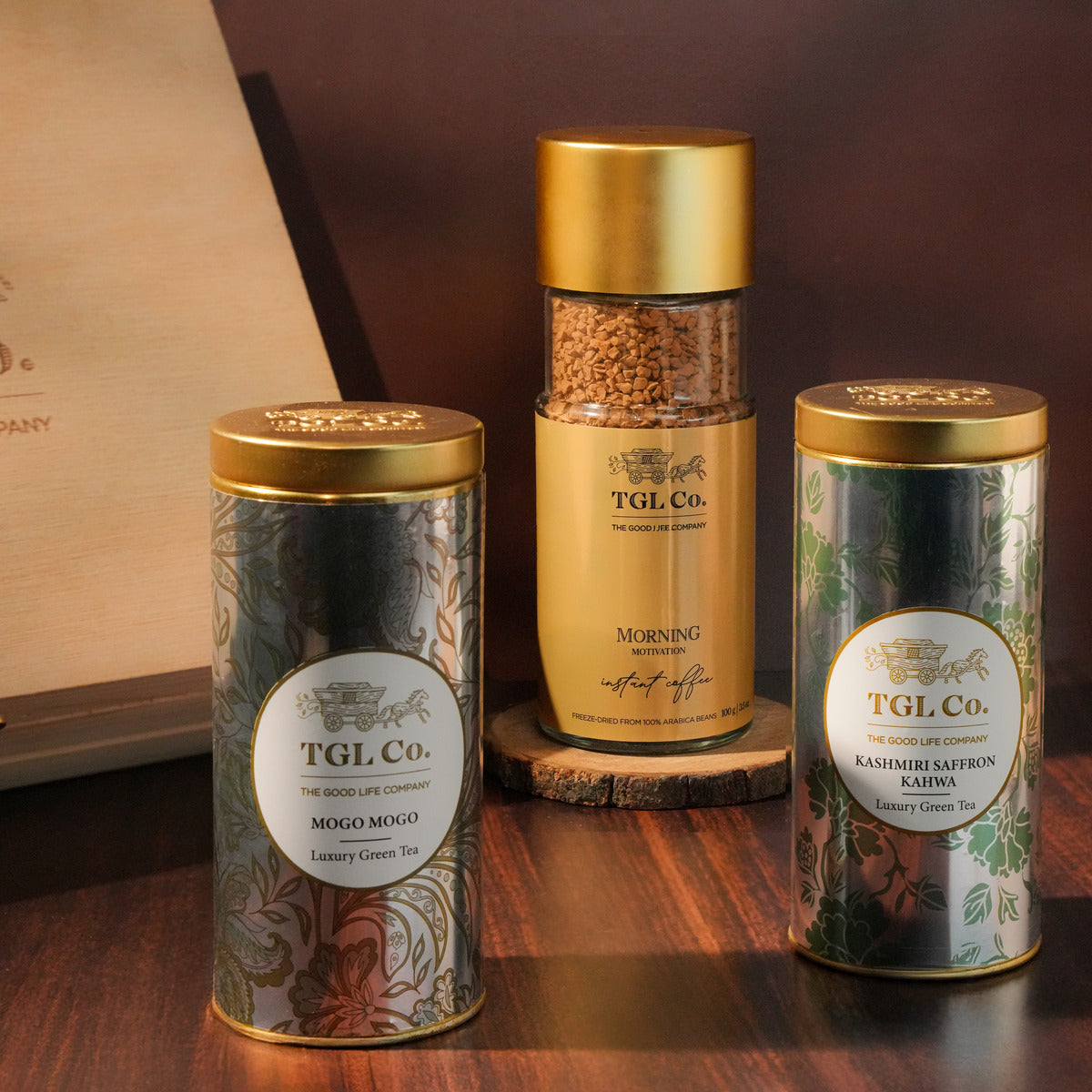 Three TGL Co. tea canisters on a wooden surface with a blurred background