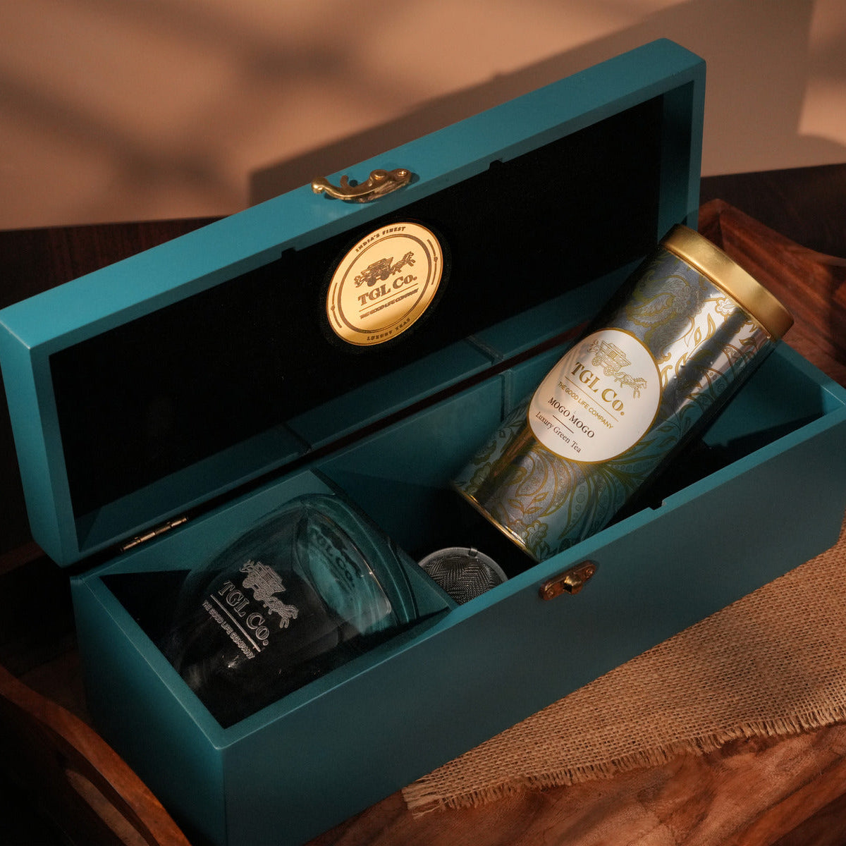 Teal gift box with a bottle and can inside, featuring a visible brand logo.